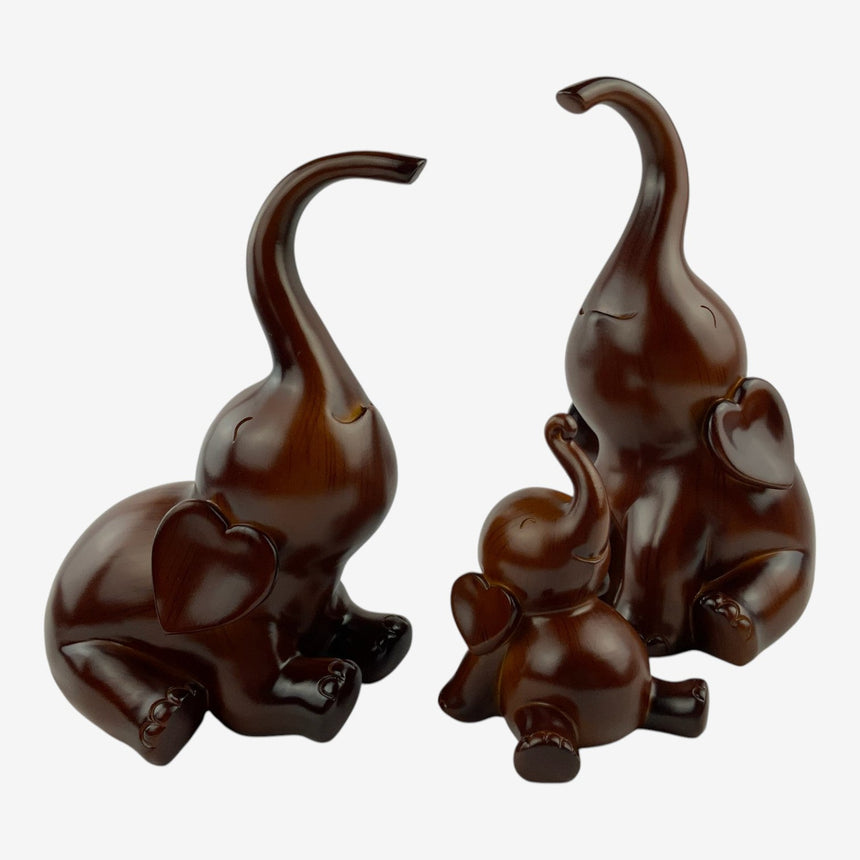 Sitting Wood Elephant Figurines Set of 3, angled view of the calf reaching toward a larger seated figure