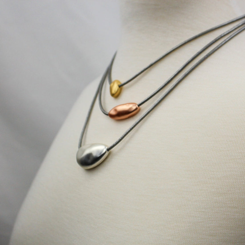 Three-Layer Pebble Necklace — Mixed-Tone Alloy, Gray Cords, angled view of three graduated strands on a mannequin