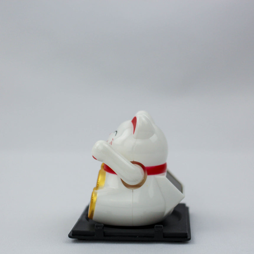 Solar Fortune Cat with Koban Coin and Fan, white side profile facing left with raised paw, red collar, and coin edge visible