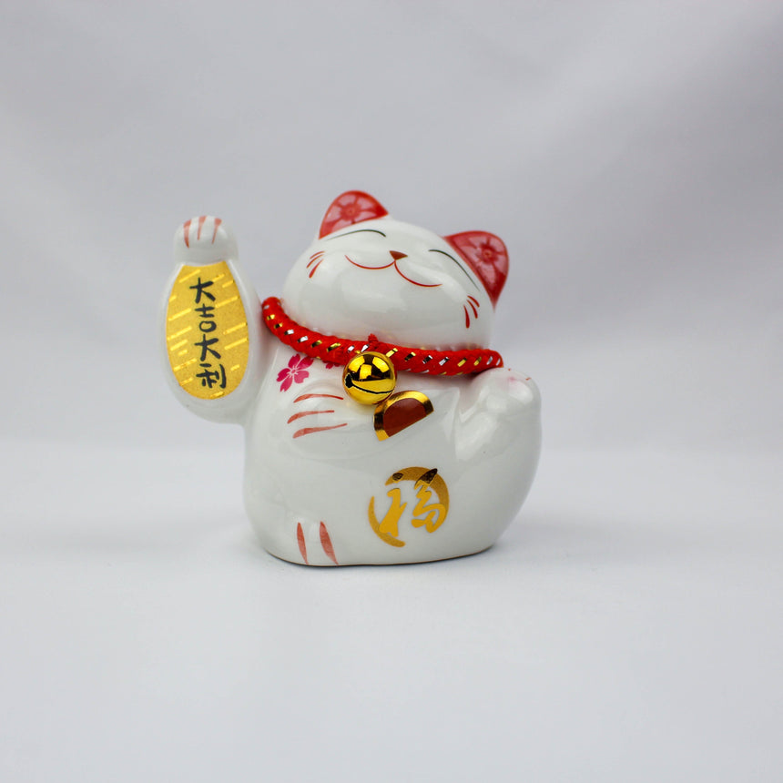 Da Ji Da Li Ceramic Lucky Cat Coin Bank, white glazed front view raising a gold banner, red bead collar with bell