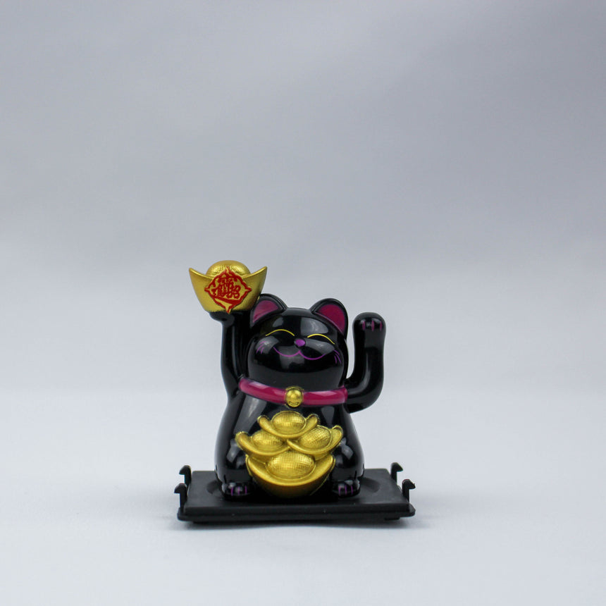 Solar Fortune Cat with Raised Ingot, black front view, ingot lifted high over stacked gold at the belly, pink collar